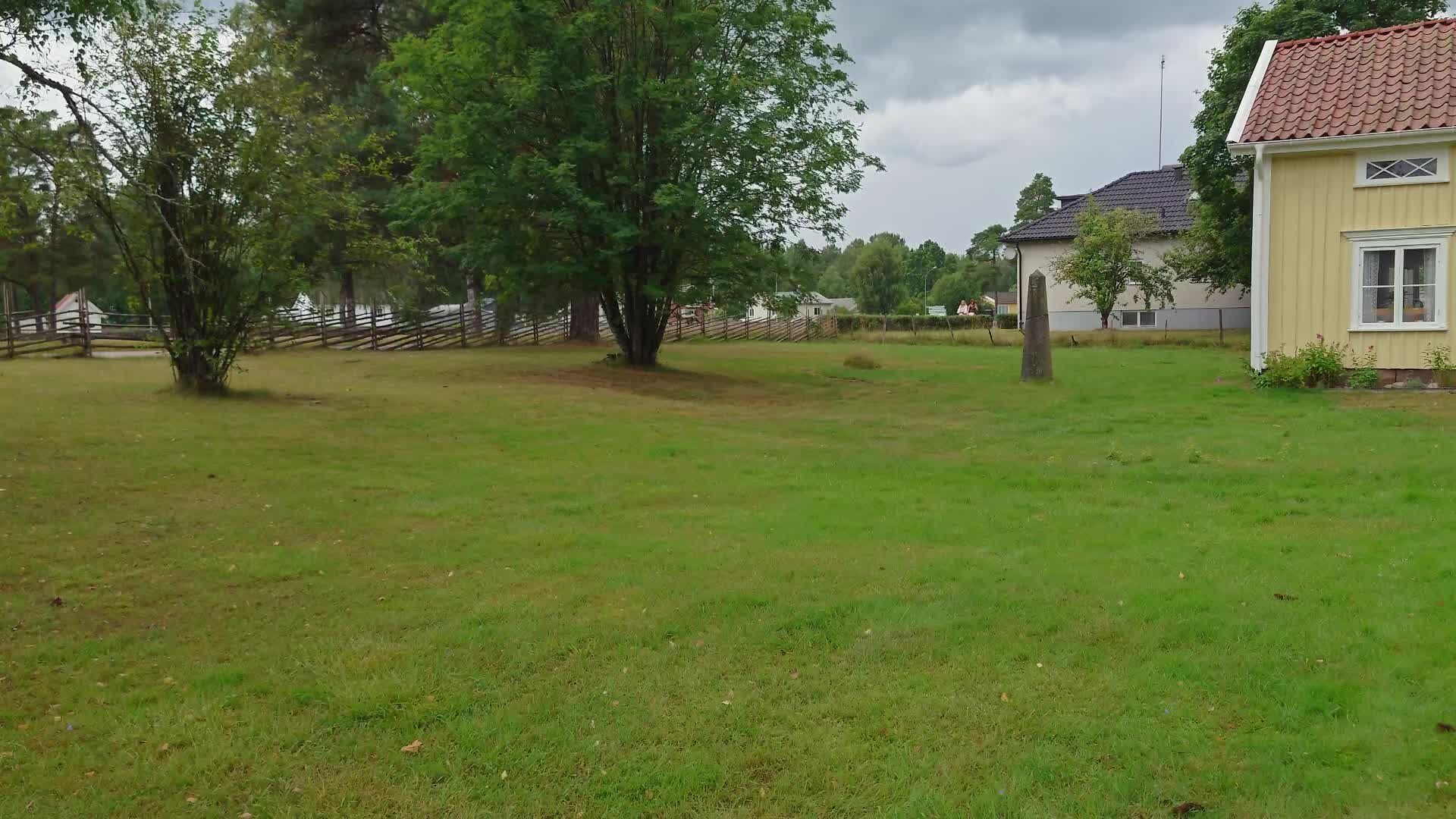 Den resta stenen vid domarringen, med den gula stugan i bakgrunden