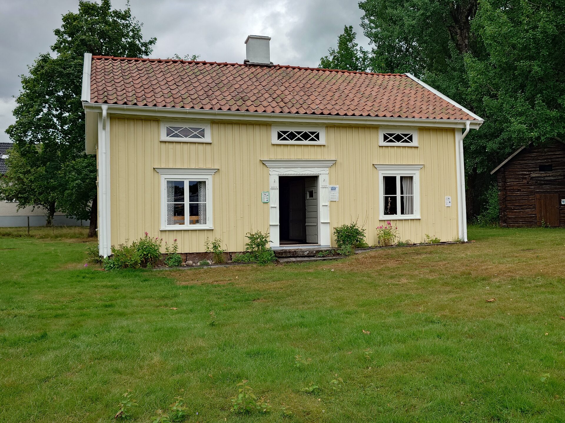 Gulmålad stuga med vit snickarglädje