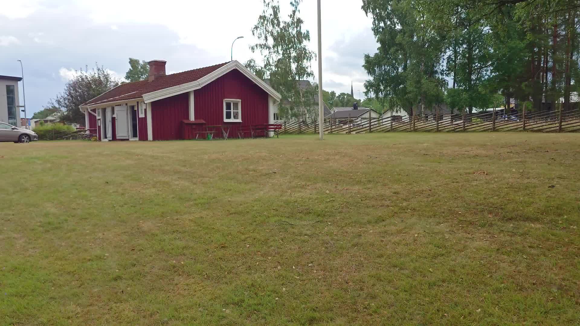 Rödmålad stuga med picknickbord och flaggstång